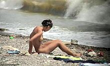 Tummatukkainen alaston poikasen kävely noin alasti rannalla