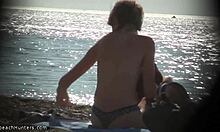 Blondharige nudist stript op het strand