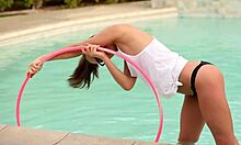 Okuliarnatá tínedžerská priateľka pózuje s hula hoop v bazéne