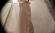 Långbent brunett tar på sig sina kläder igen efter att ha strippat i ett omklädningsrum