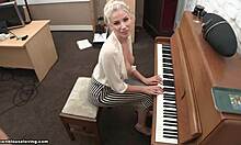 Polne prsi blondinke padejo ven, medtem ko igra klavir pred kamero