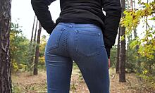 Nastoletnia dziewczyna w niebieskich dżinsach prowokuje do pokazania swoich jędrnych pośladków w zalesionej okolicy